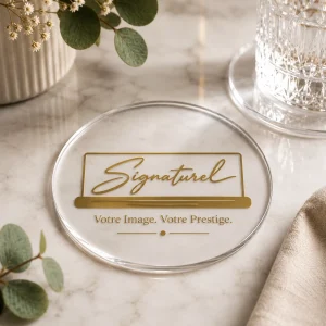 Dessous de verre personnalisé (sous-tasse personnalisée) en acrylique transparent rond avec logo doré, posé sur une table en marbre